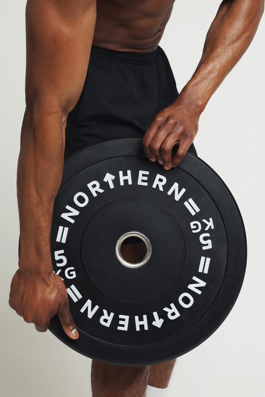 Athlete holding bumper plates features high density rubber coating for durability