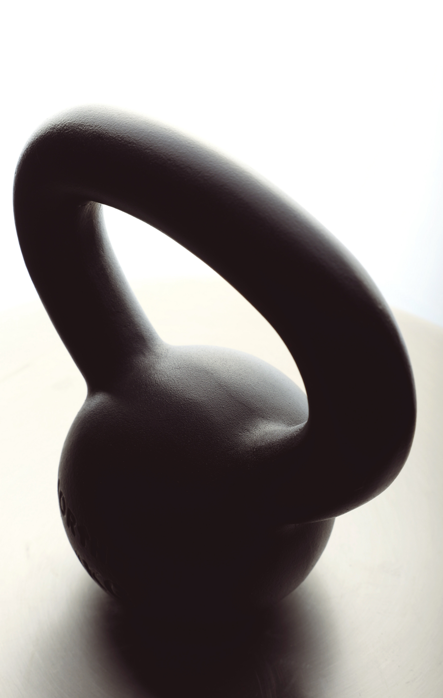 Cast iron kettlebell on the floor features compact design and wider handle