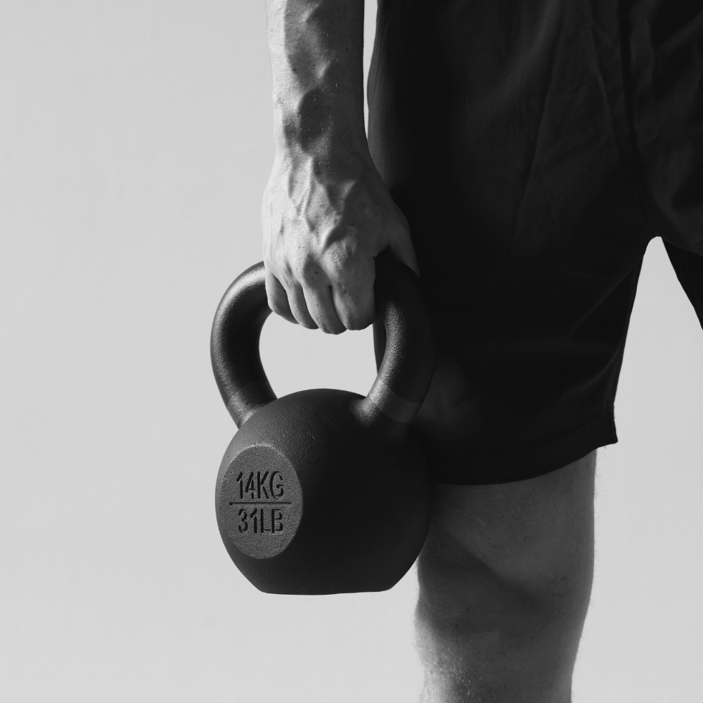 Athlete gripping a heavy duty kettlebell with engrave weight marking