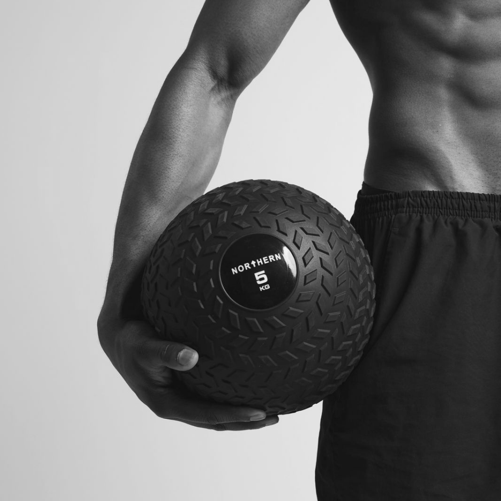 Athlete holding tyre-tread design slam ball after a intense workout