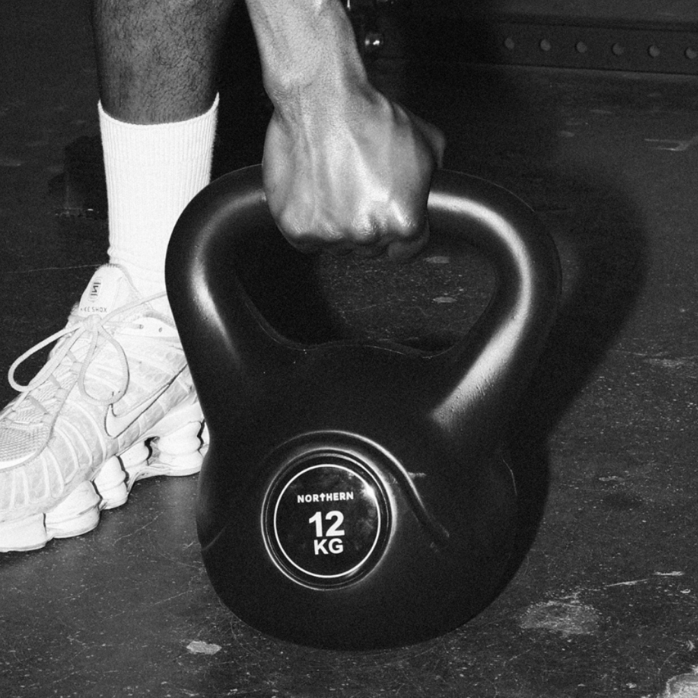 Vinyl-coated kettlebell pickup from the gym floor during deadlift workout